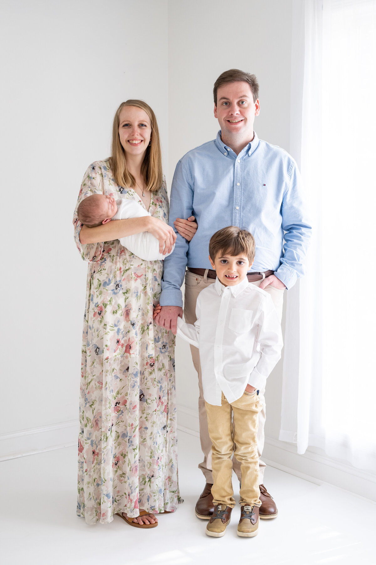 A family with their newborn baby posing for their first family picture