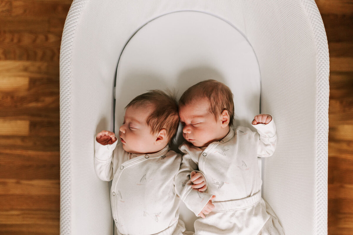 newborn photos of twin boys snuggled in a snoo together