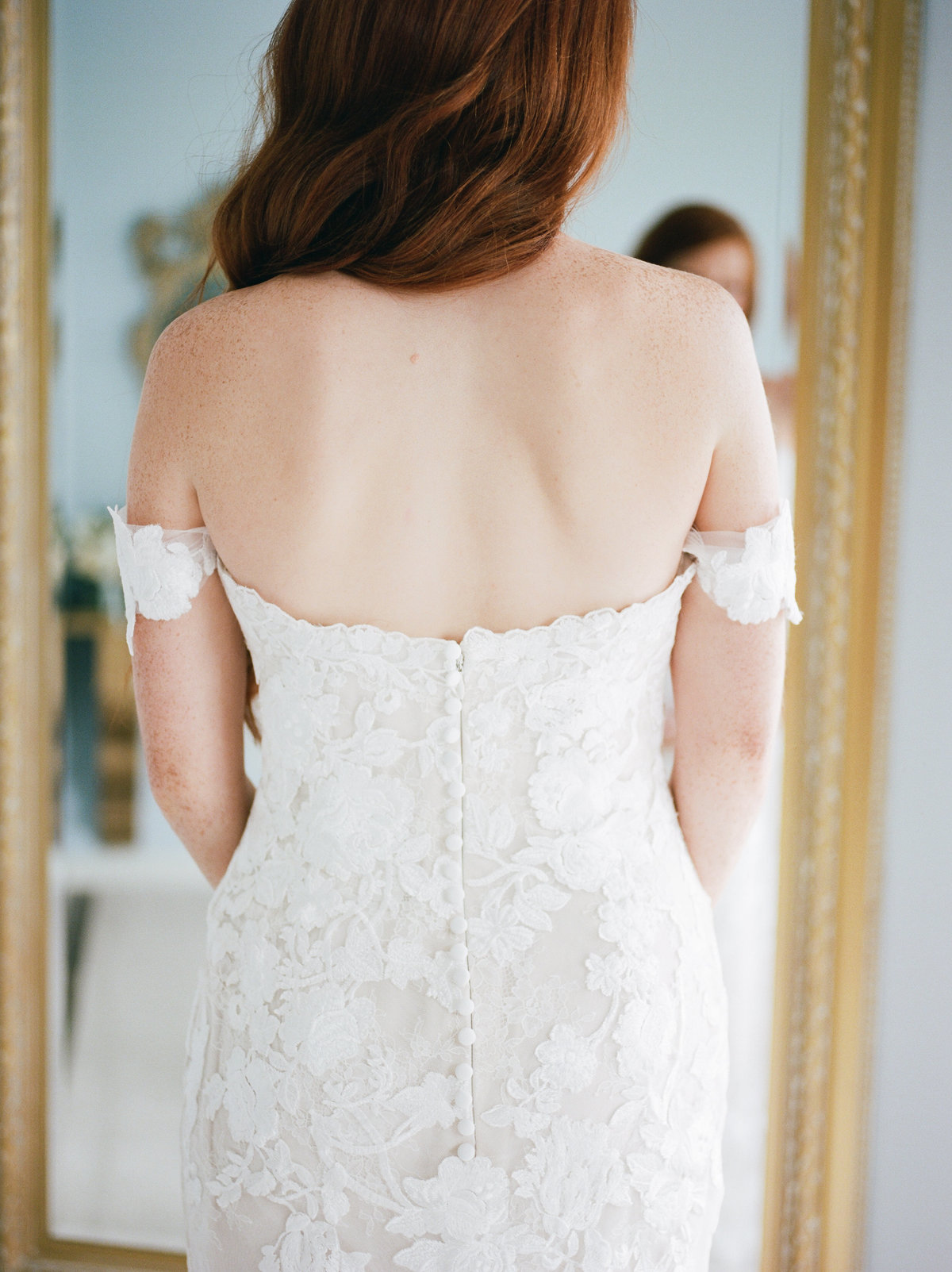 bride looking in mirror showing back of strapless gown