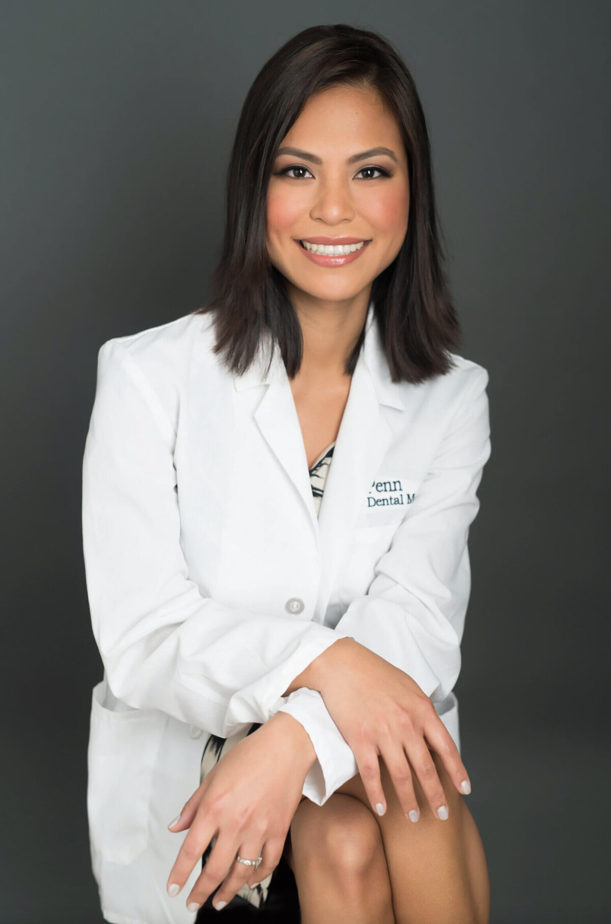 Female dentist posing for a professional headshot on a gray background in a New Jersey studio