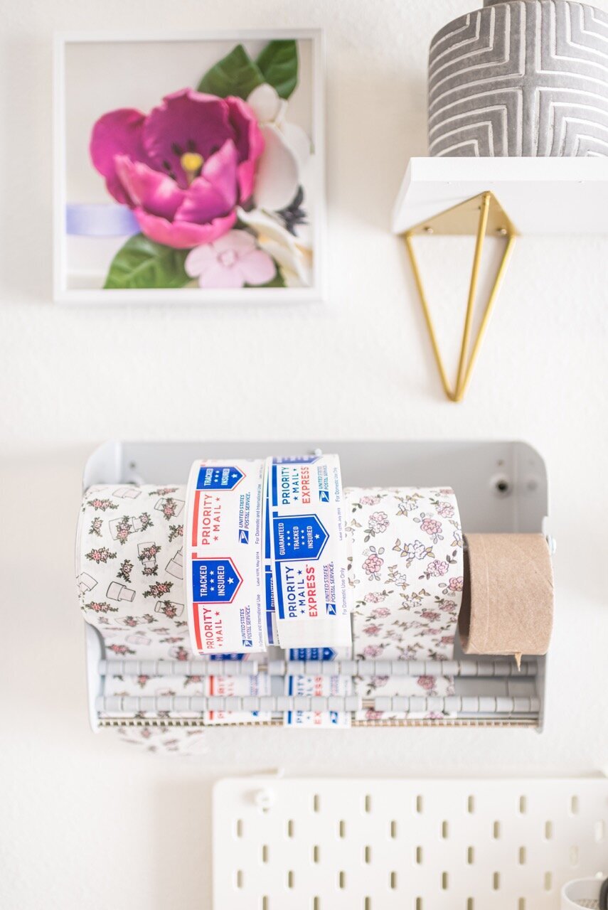 Shipping tape and labels organized on a wall with photos of gumpaste flowers