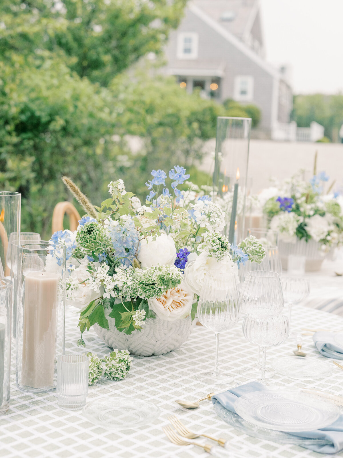 Wedding reception table setting with clear plates, blue napkins, and blue and white floral centerpieces