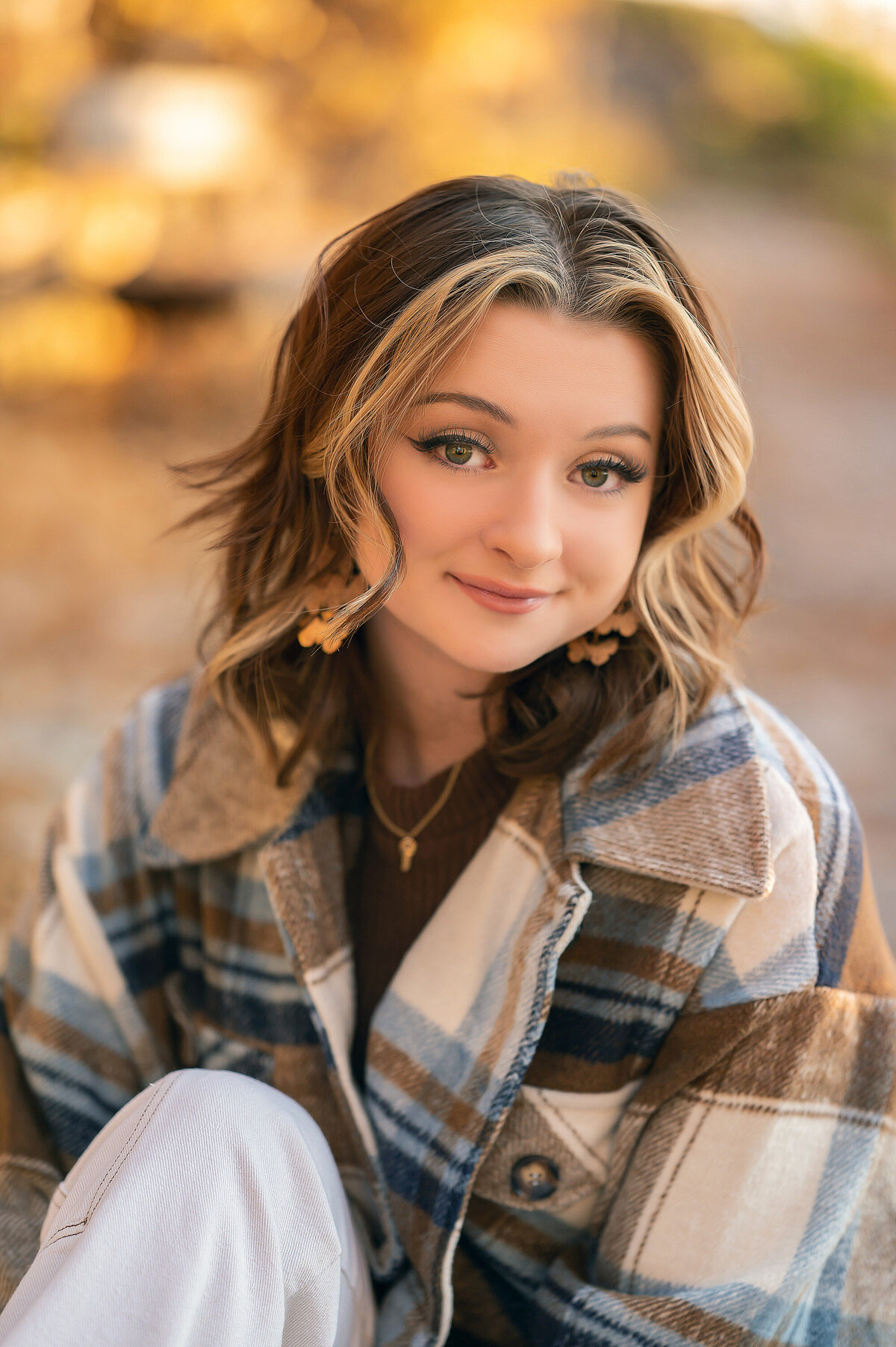 A young lady from Waukesha South sits in Minooka Park wearing a flannel jacket in the peak of autumn.