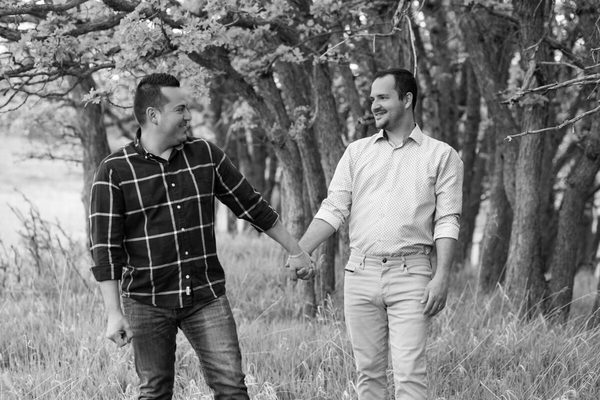 husbands standing together holding hands in a forest
