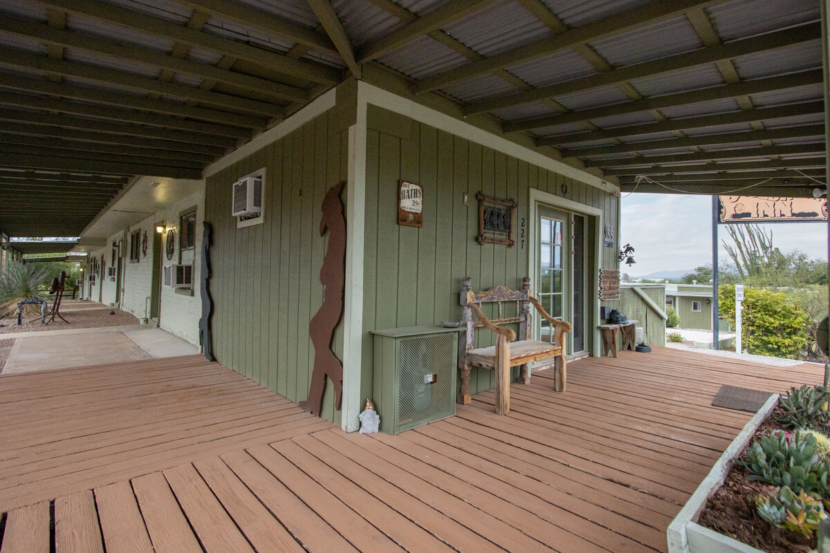 A green building with a wooden deck and a chair on it