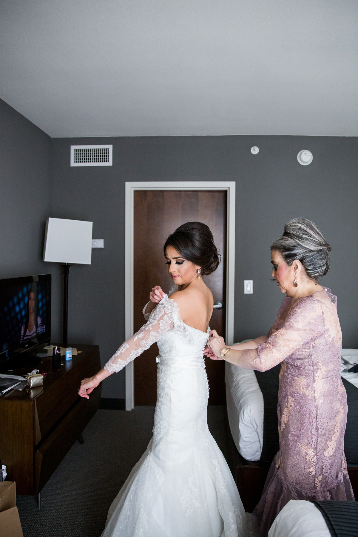 Mother of bride helps her daughter put on wedding gown before wedding ceremony at Contessa Hotel in downtown San Antonio