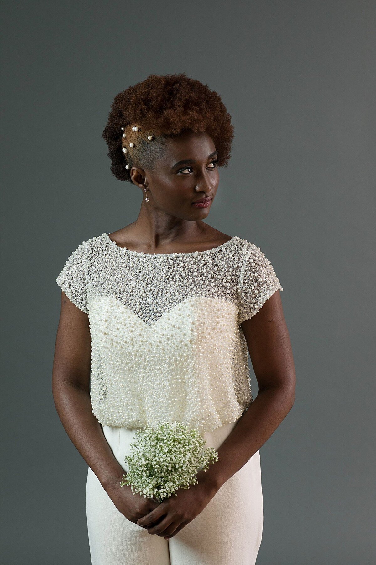 Close-up of the front of the Jonah bridal jumpsuit bodice. The pearl net topper features a bateau neckline. The strapless foundation is visible under the semi-sheer topper.