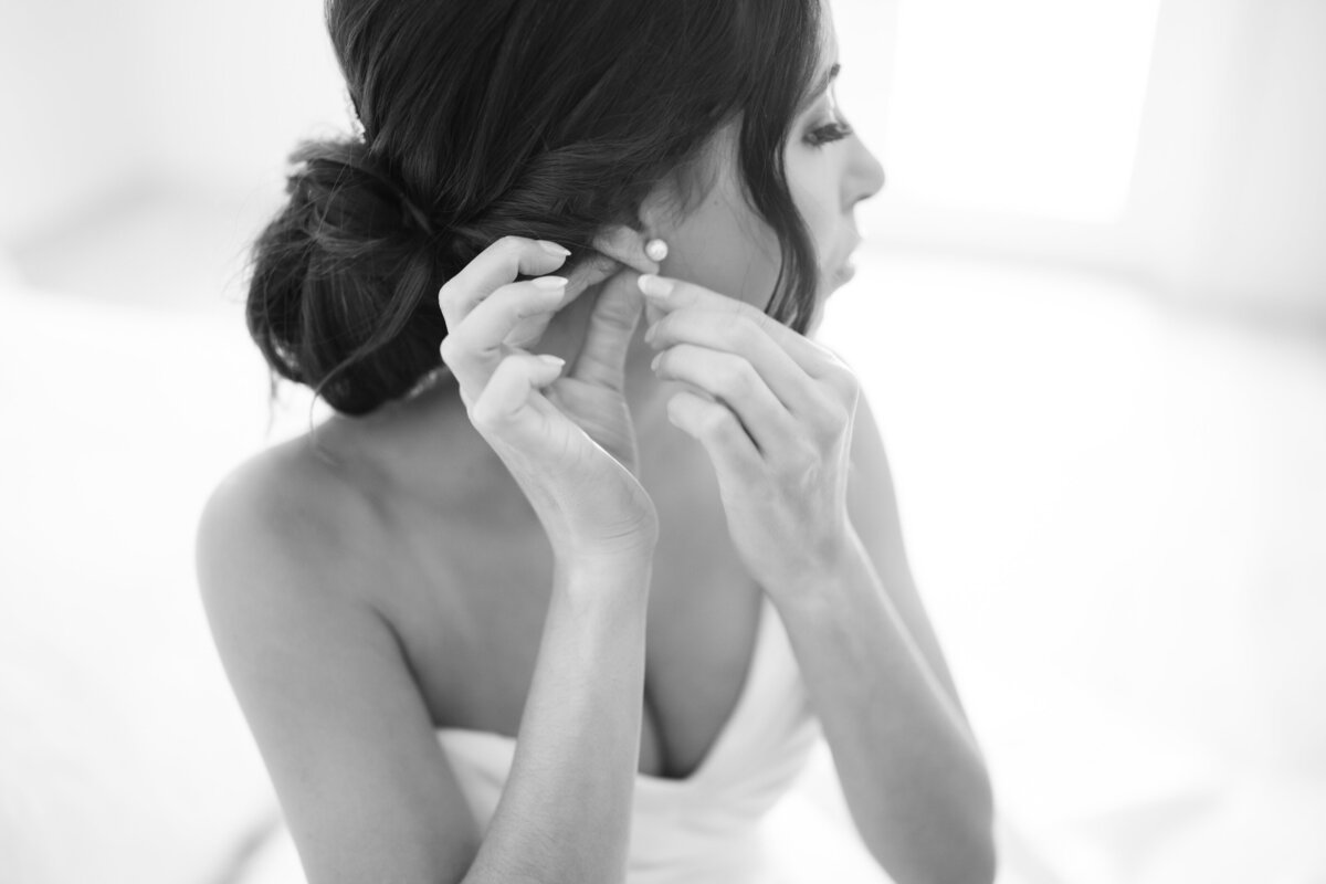 Bride putting on pearl earrings