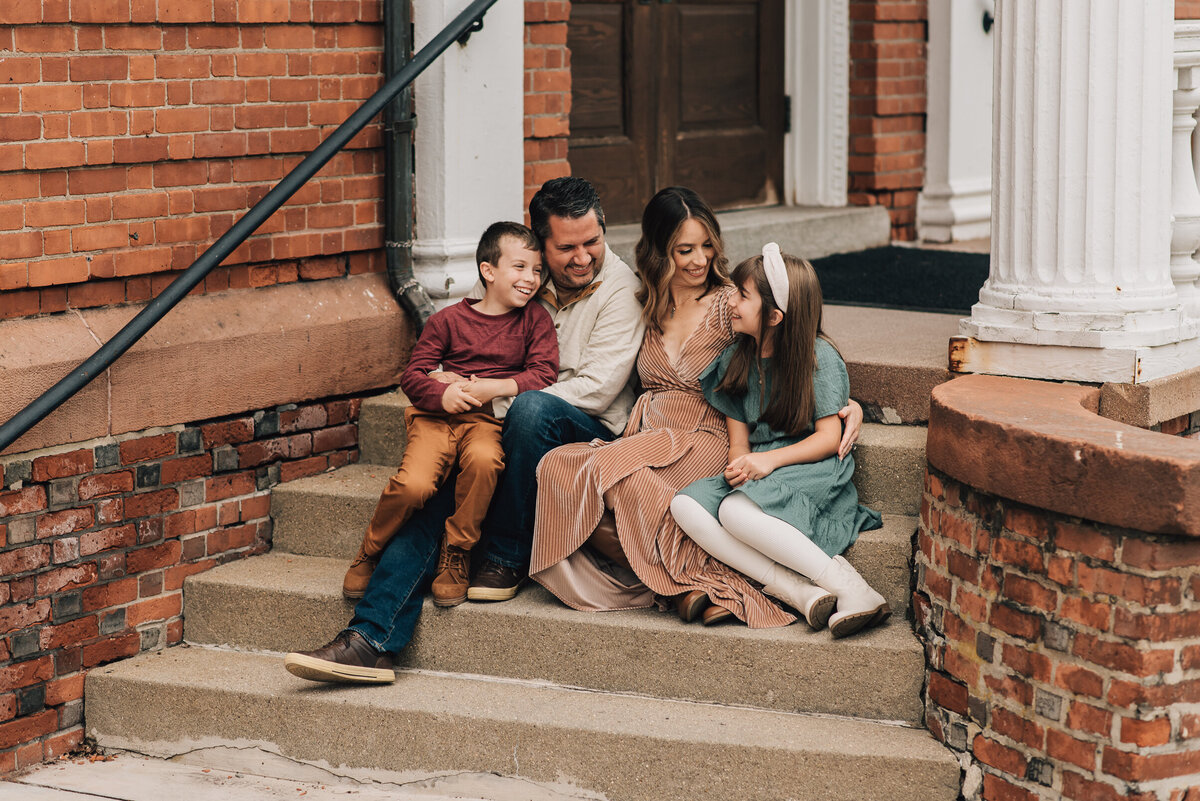 A family of four smiling at each other at their family session in Canton, Connecticut.