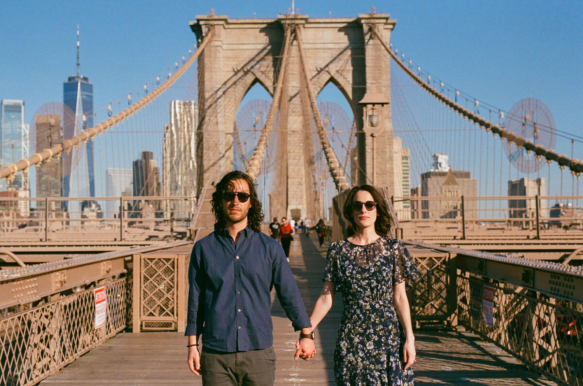 A couple holding hands while standing on a bridge.