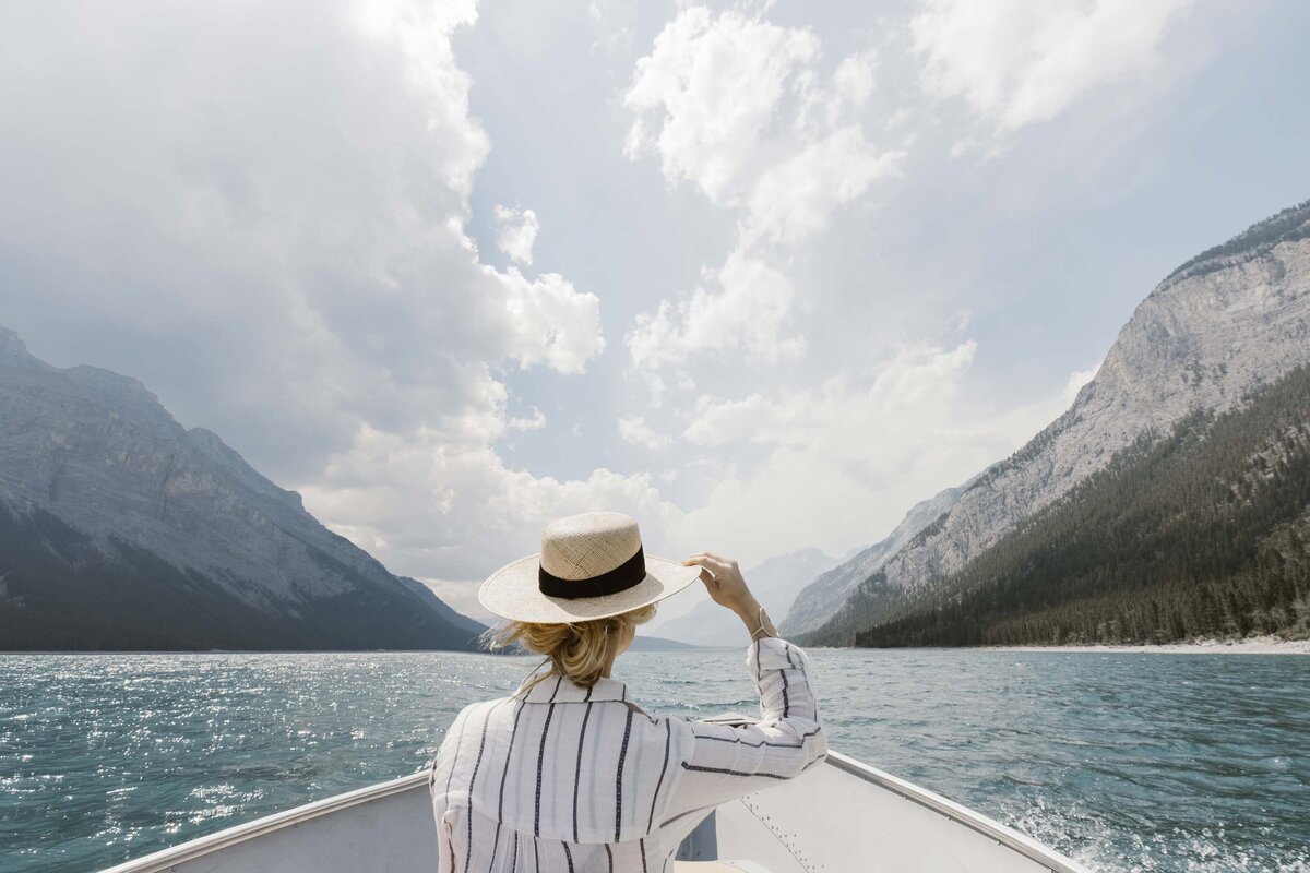 Woman on boat looks out into mountainous  ocean landscape.