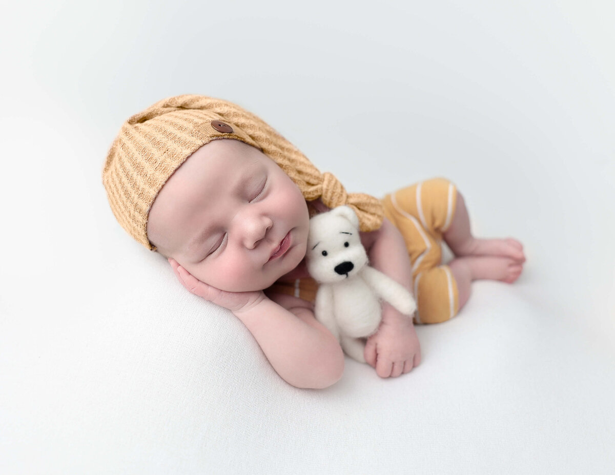 Newborn boy posed with a teddy bear at our Rochester, Ny studio.