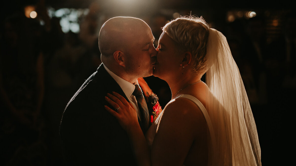 A bride and groom kiss during their first dance at Clapton Country Club in London.