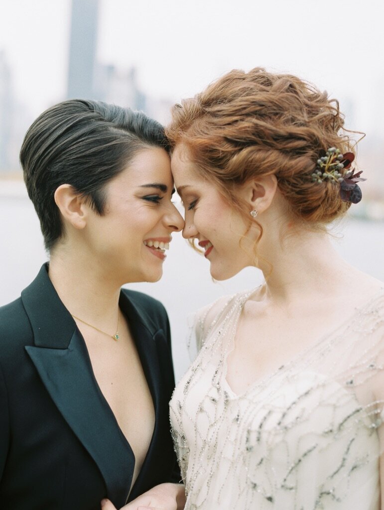 Red curly hair bride with it up and flowers in hair and one bride with short dark hair