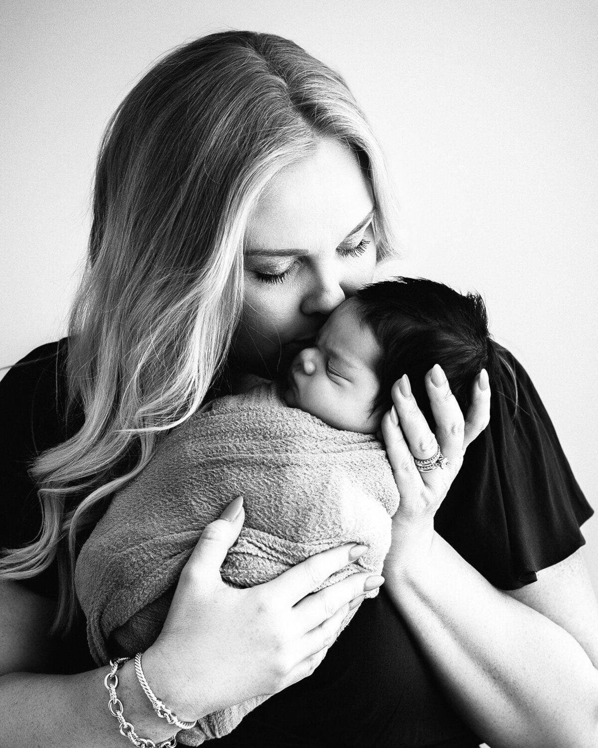 black and white image of mom kissing her baby