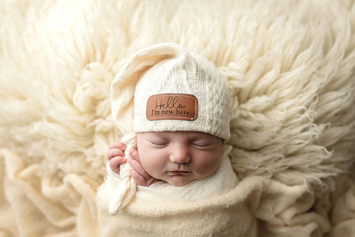 Newborn girl holding sleepy cap top.