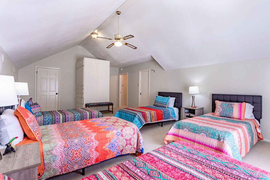 Bedroom with five beds and comfortable bedding in this 5-bedroom, 4-bathroom vacation rental house for 16+ guests with pool, free wifi, guesthouse and game room just 20 minutes away from downtown Waco, TX.