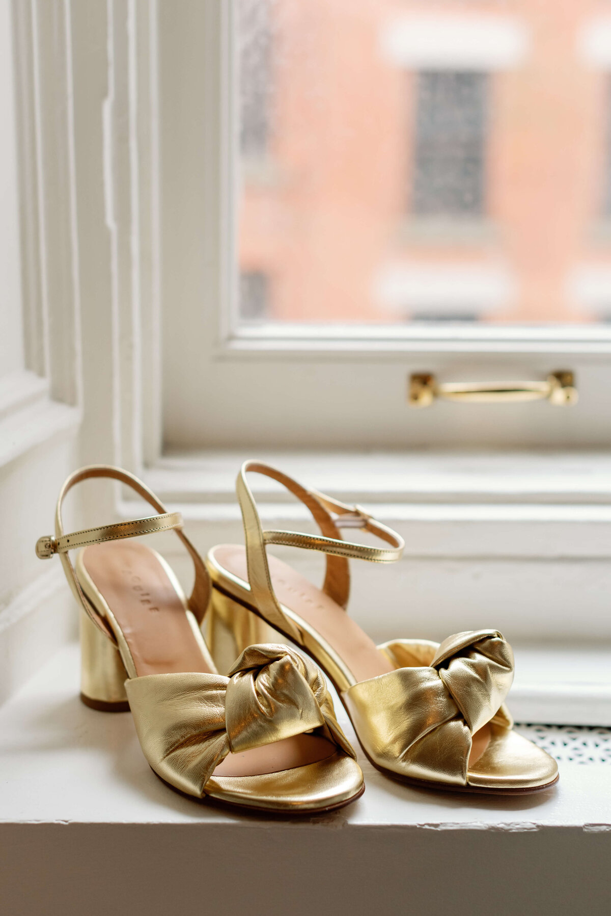 Gold wedding shoes sitting on a window ledge at  at Halifax Club wedding in Nova Scotia