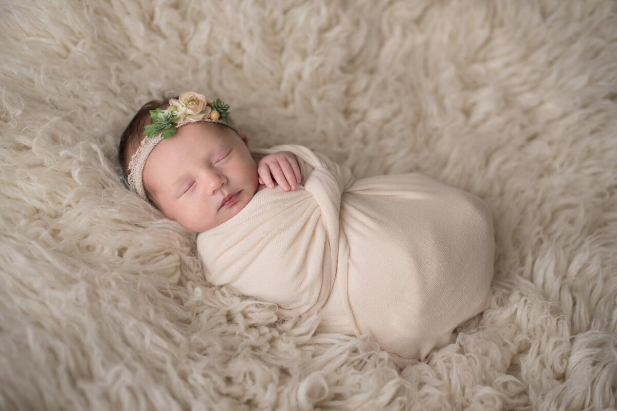 Wrapped newborn in cream  colored furry background