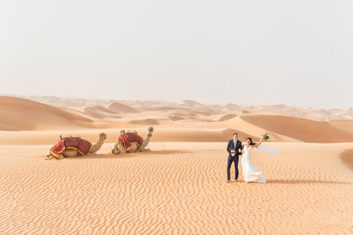 Bride and groom celebrating their wedding amidst the Arabian dunes in Dubai for an elopement photoshoot organized by Lovely & Planned