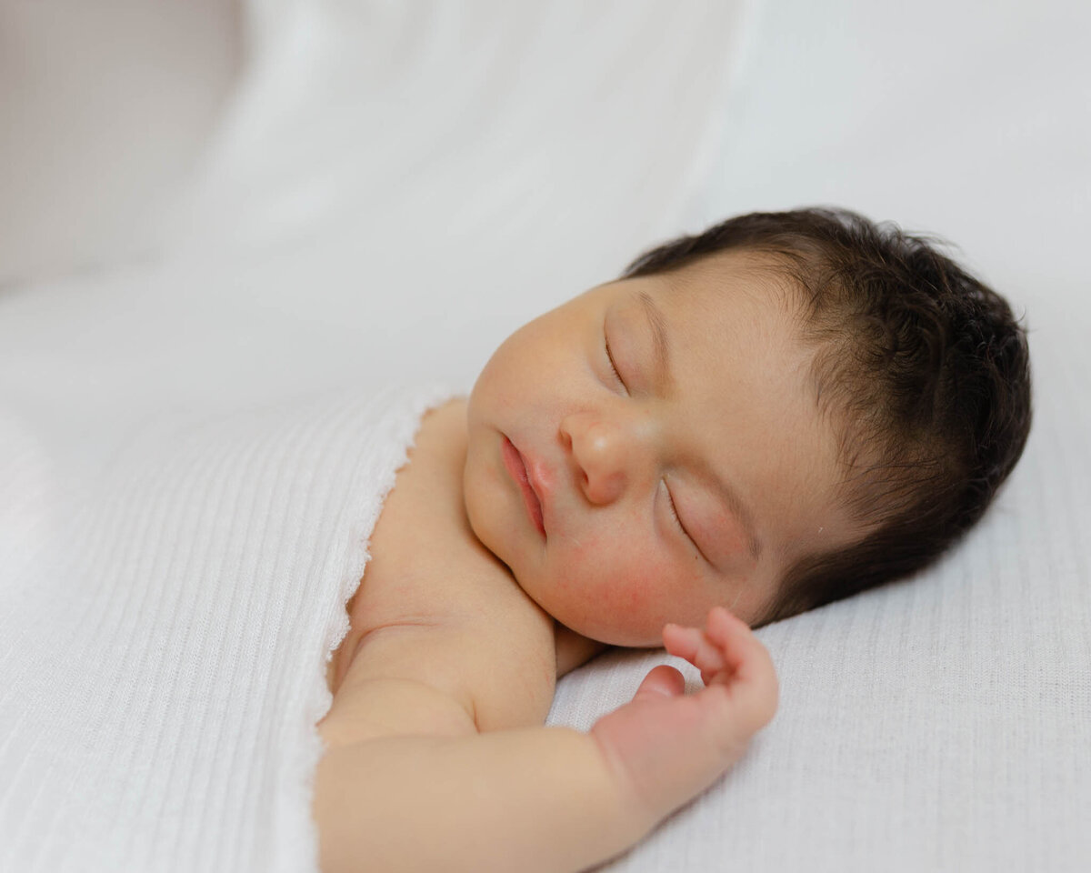 newborn baby sleeping on white sheets