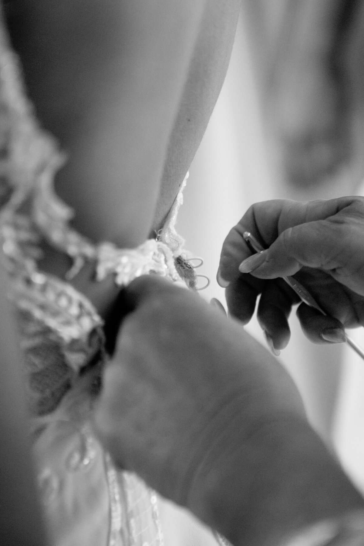 black adn white closeup of hands buttoning bride's gown New York wedding photographer Milestone Images