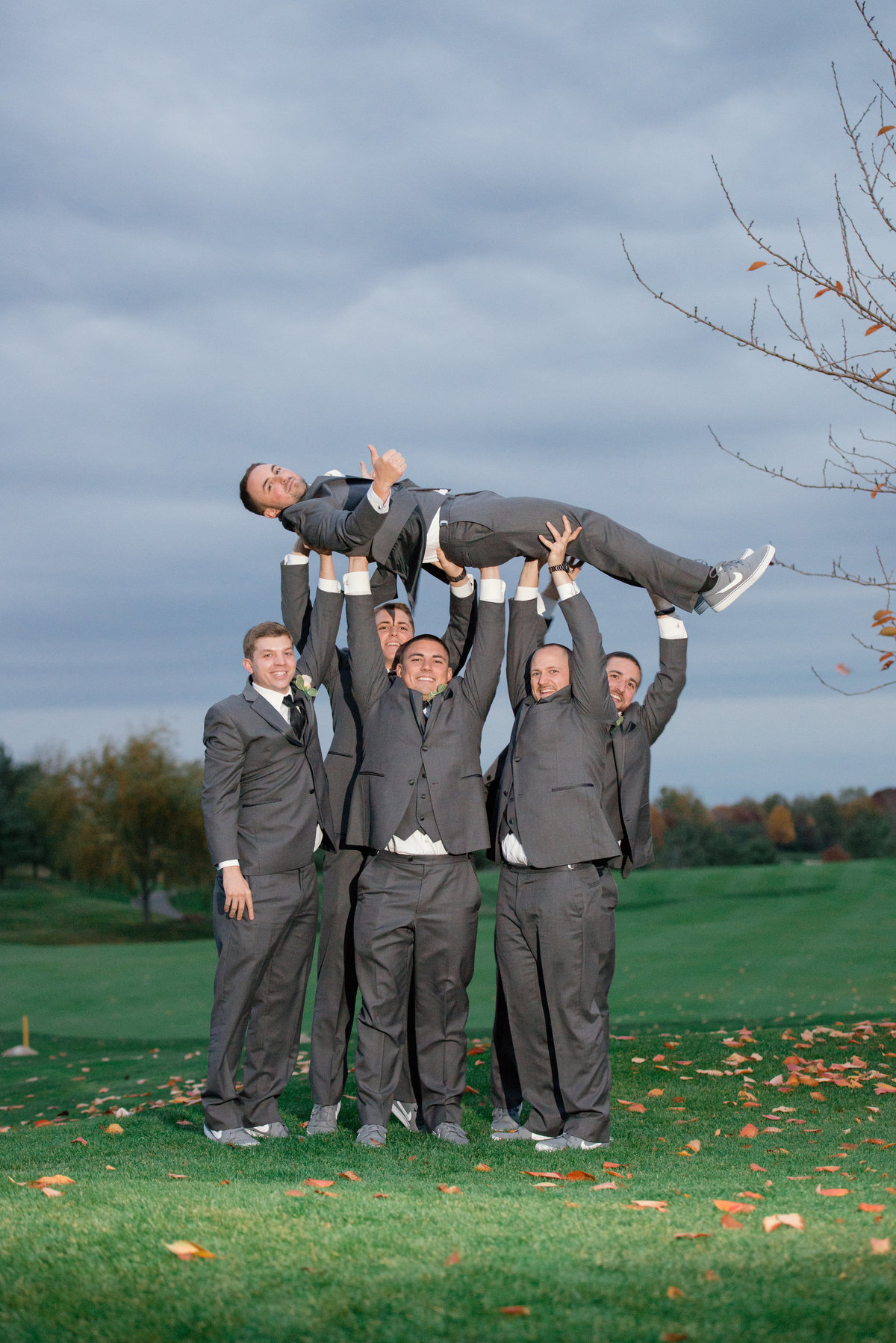 groomsmen holding up the groom on the golf course at Willow Creek Golf and Country Club