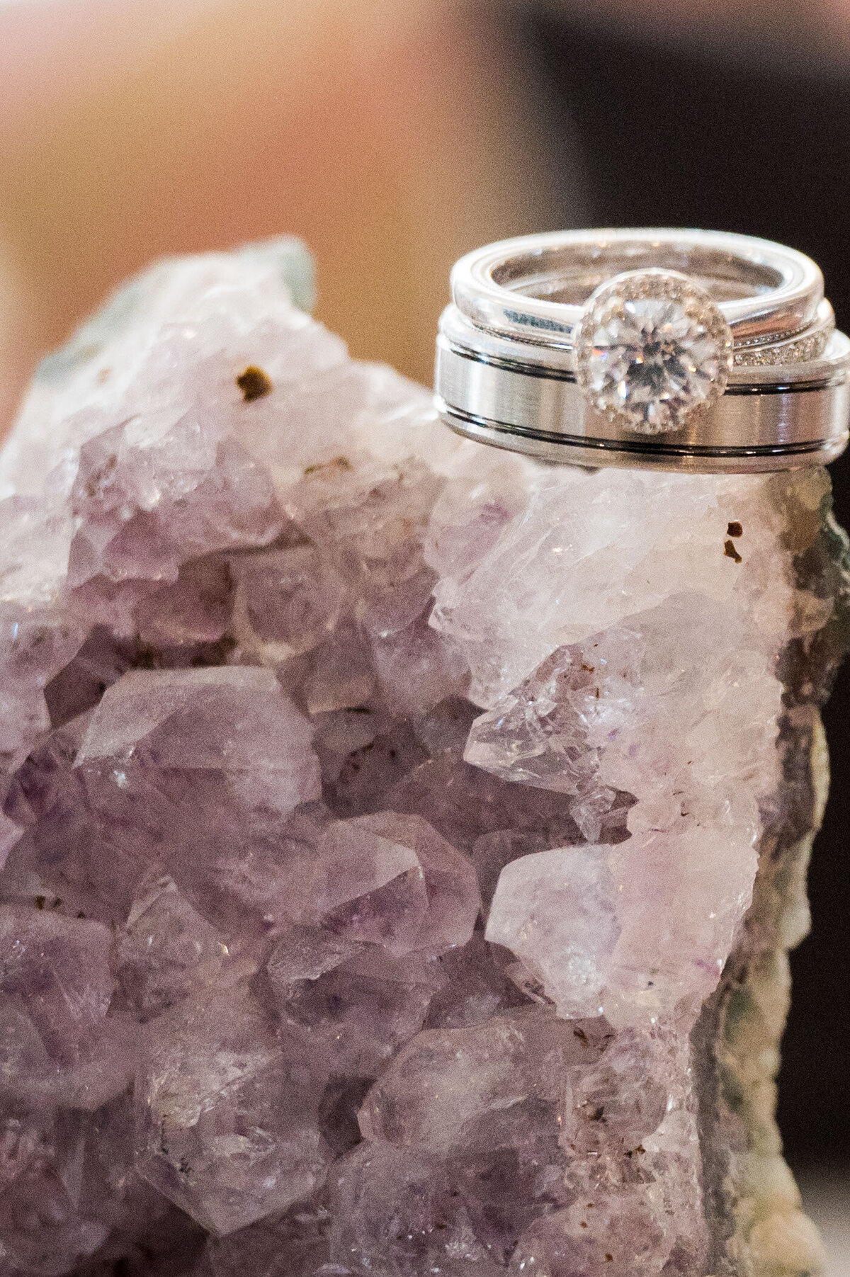 A pair of wedding rings rests on an ornate, jagged purple crystal.