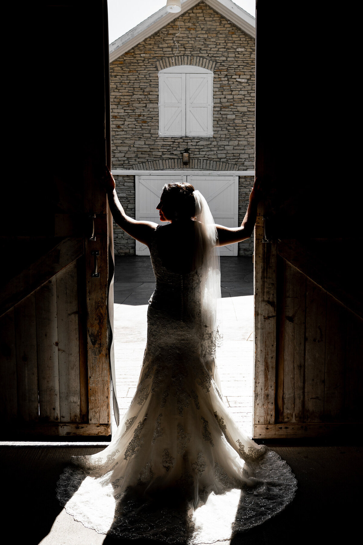 Bride stands between barn doors.