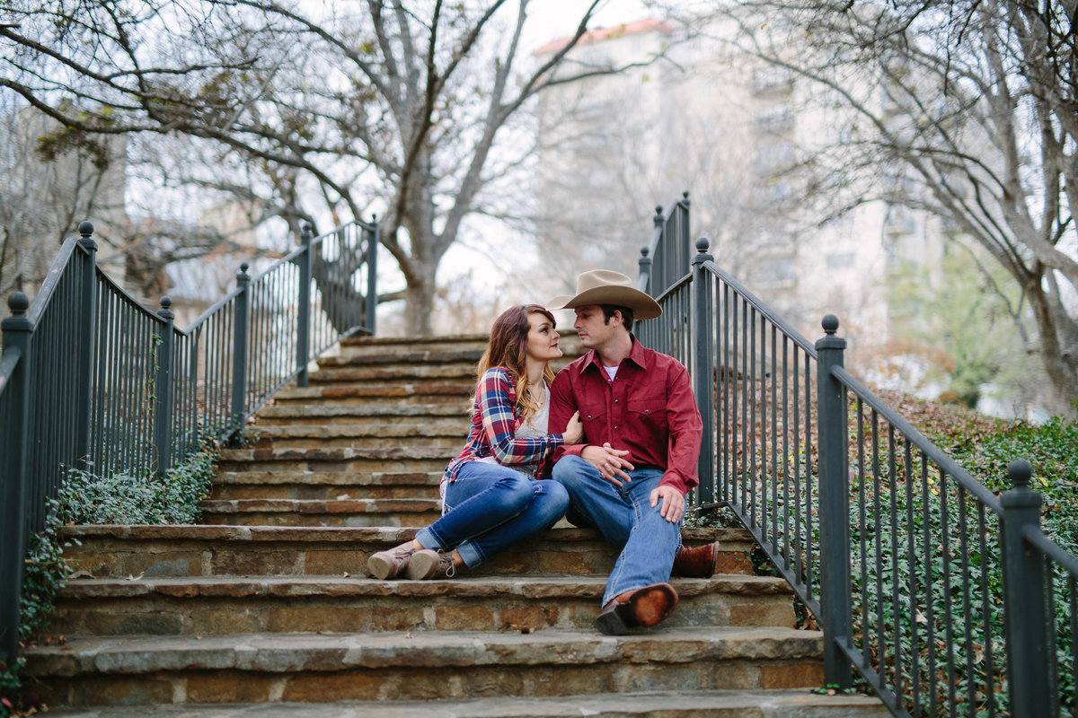 Engagement session by Expose The Heart Photography of an engaged cowboy and cowgirl sitting on the steps of the San Antonio Riverwalk.