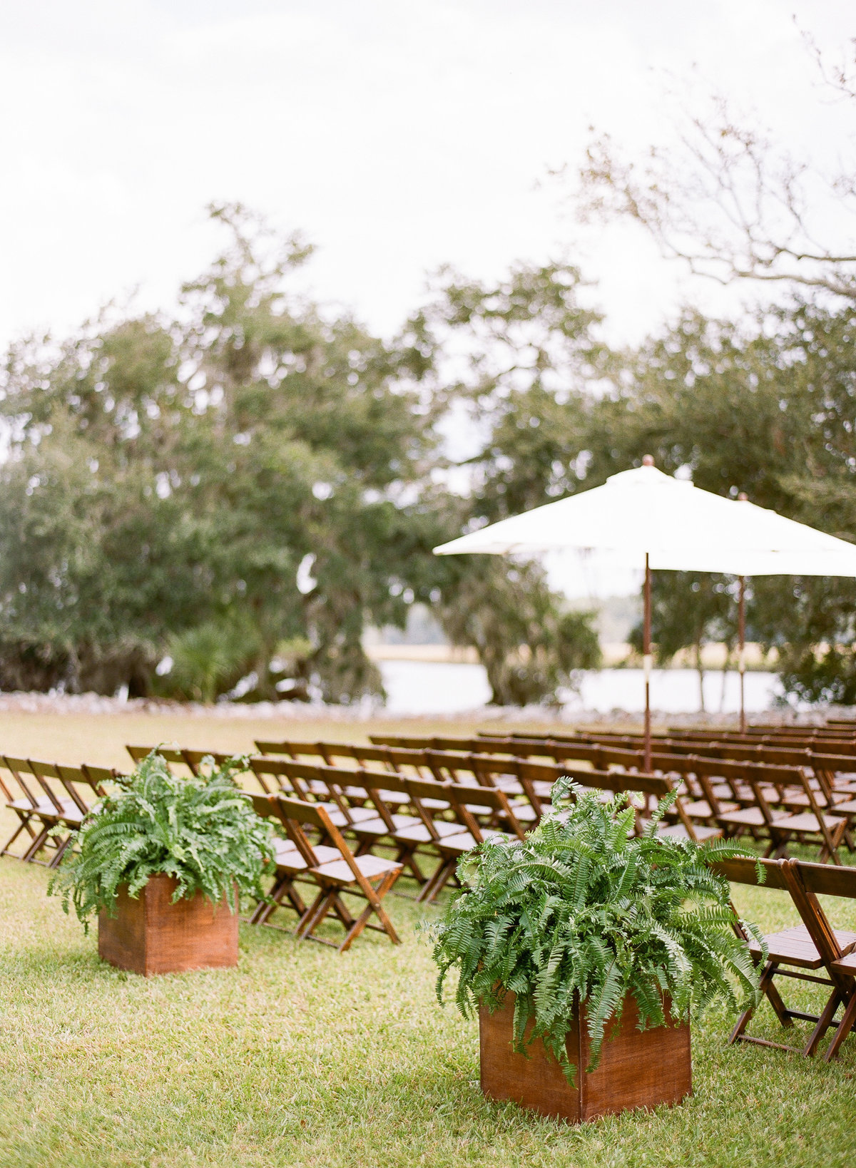 Charleston Wedding Ceremony with Beech Wood Chairs Ferns in Planters and White Umbrellas