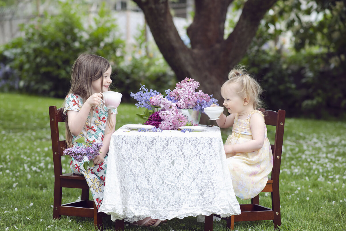 Two girls having a tea party with teacups and flowers