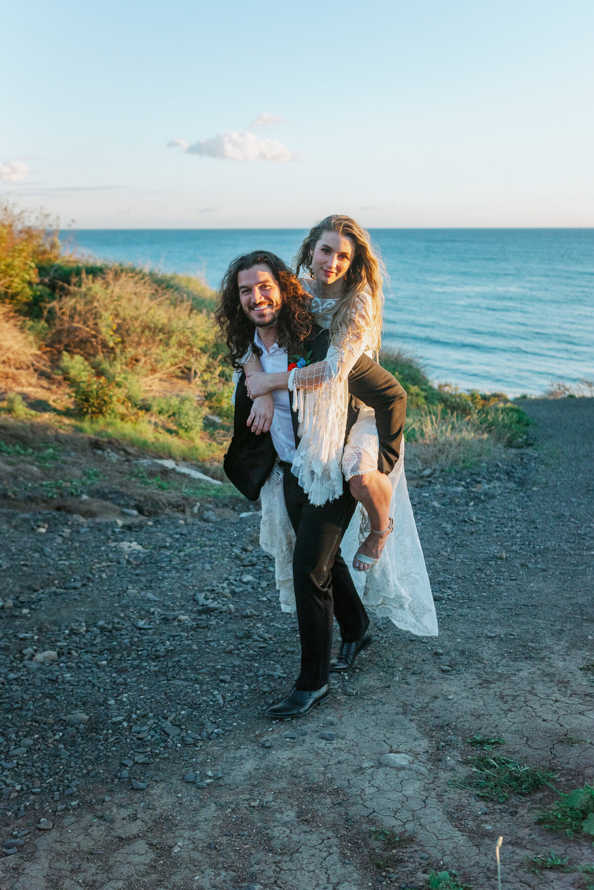 Bride and groom piggyback on Malibu cliffside