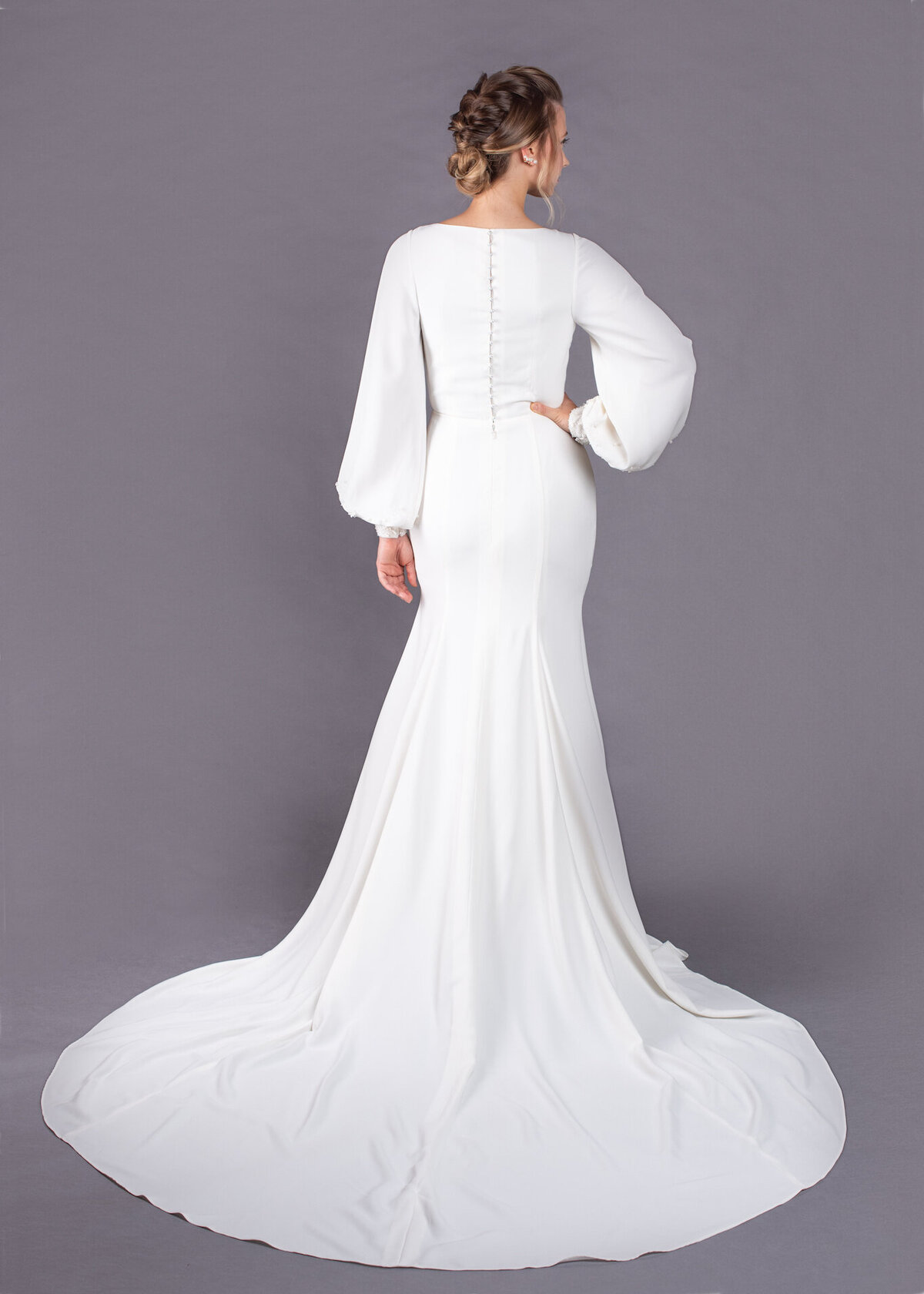 Pearl buttons close the high back on the Milly wedding dress style. The fit and flare skirt features a simple cathedral train.