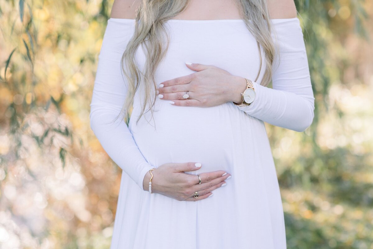 pregnant mom in white dress with diamond ring