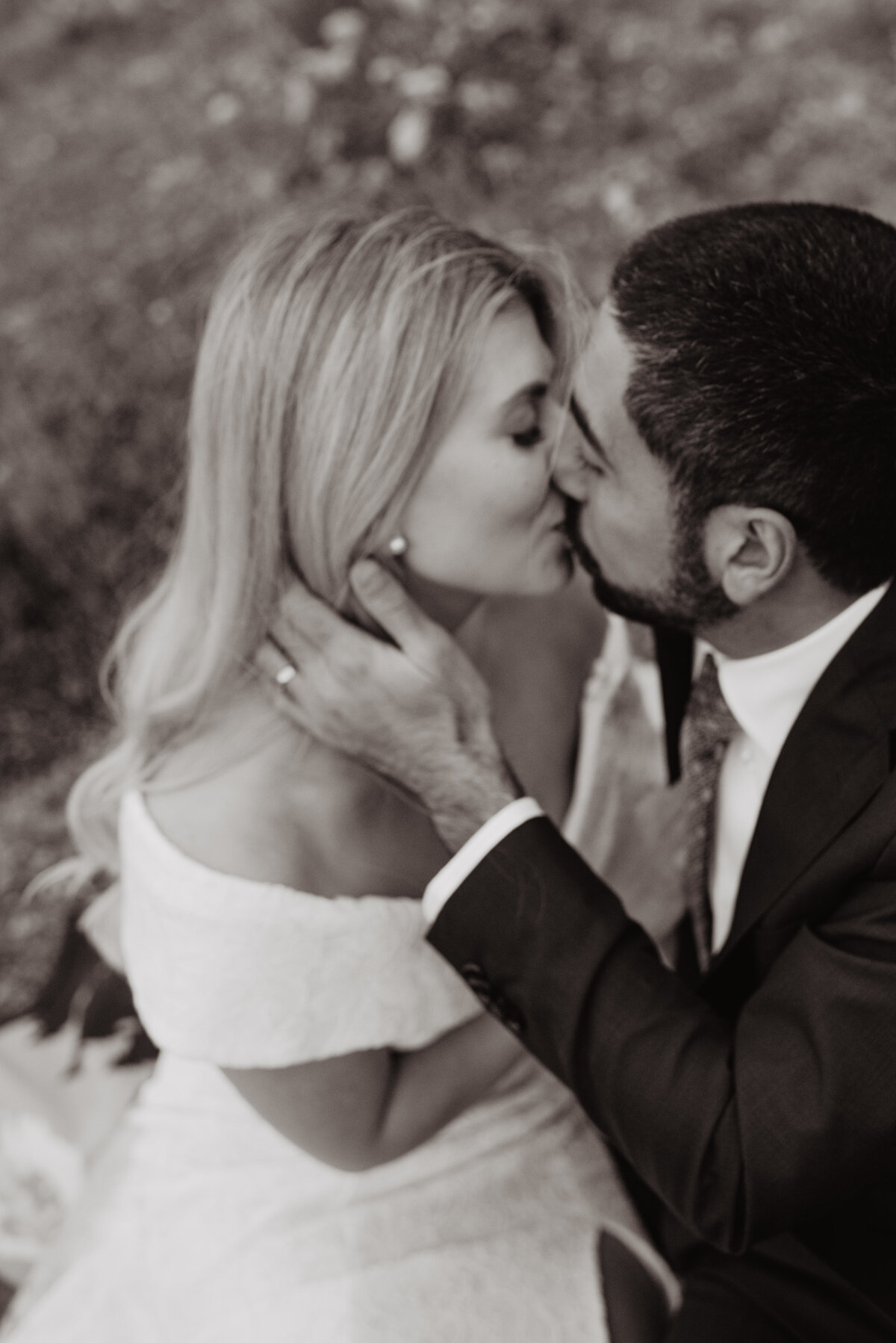 Photographers Jackson Hole capture groom kissing bride in black and white portraits