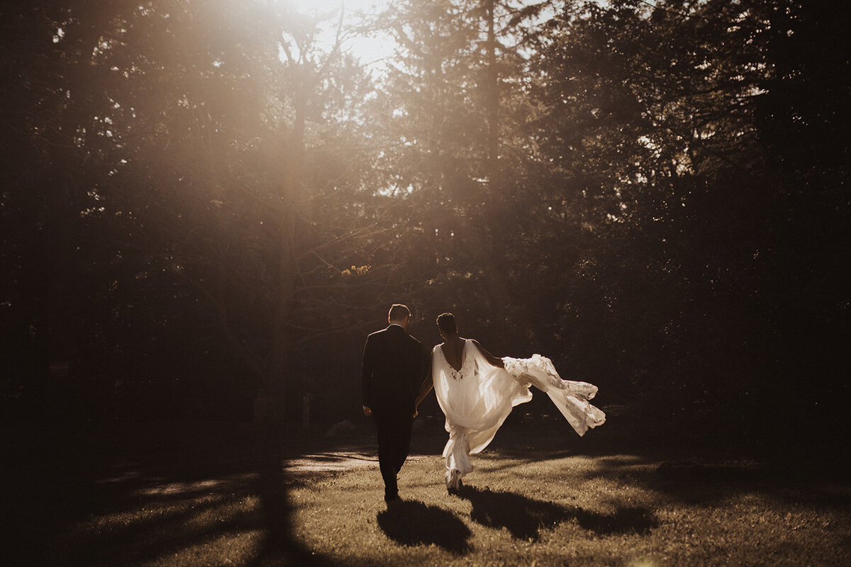 Couple walking in sunlight, bride’s dress flowing.