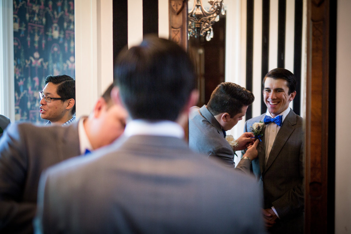 Groomsmen assist groom with tie as he gets ready for wedding ceremony at Grace Point Church