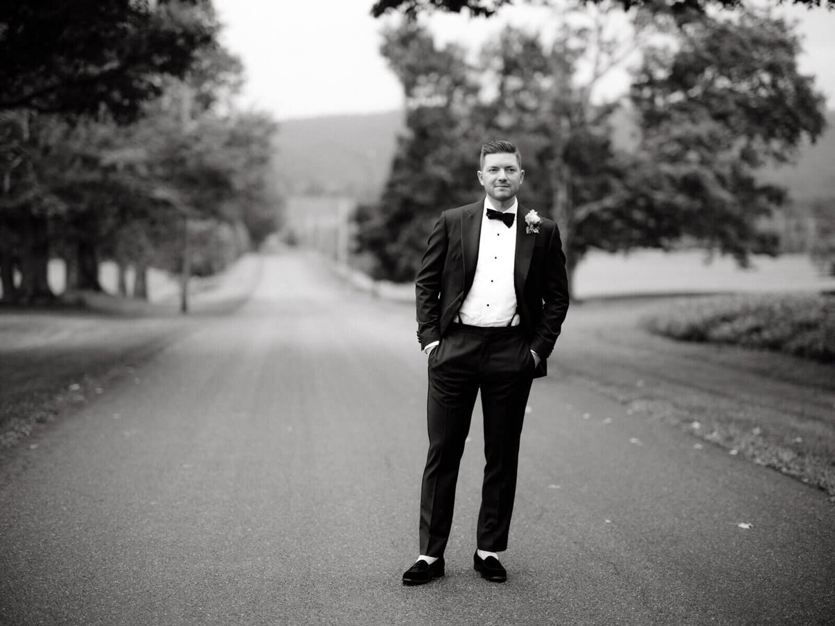 The handsome groom is standing in the middle of the rustic road at Lion Rock Farm, Sharon, CT.  Image by Jenny Fu Studio