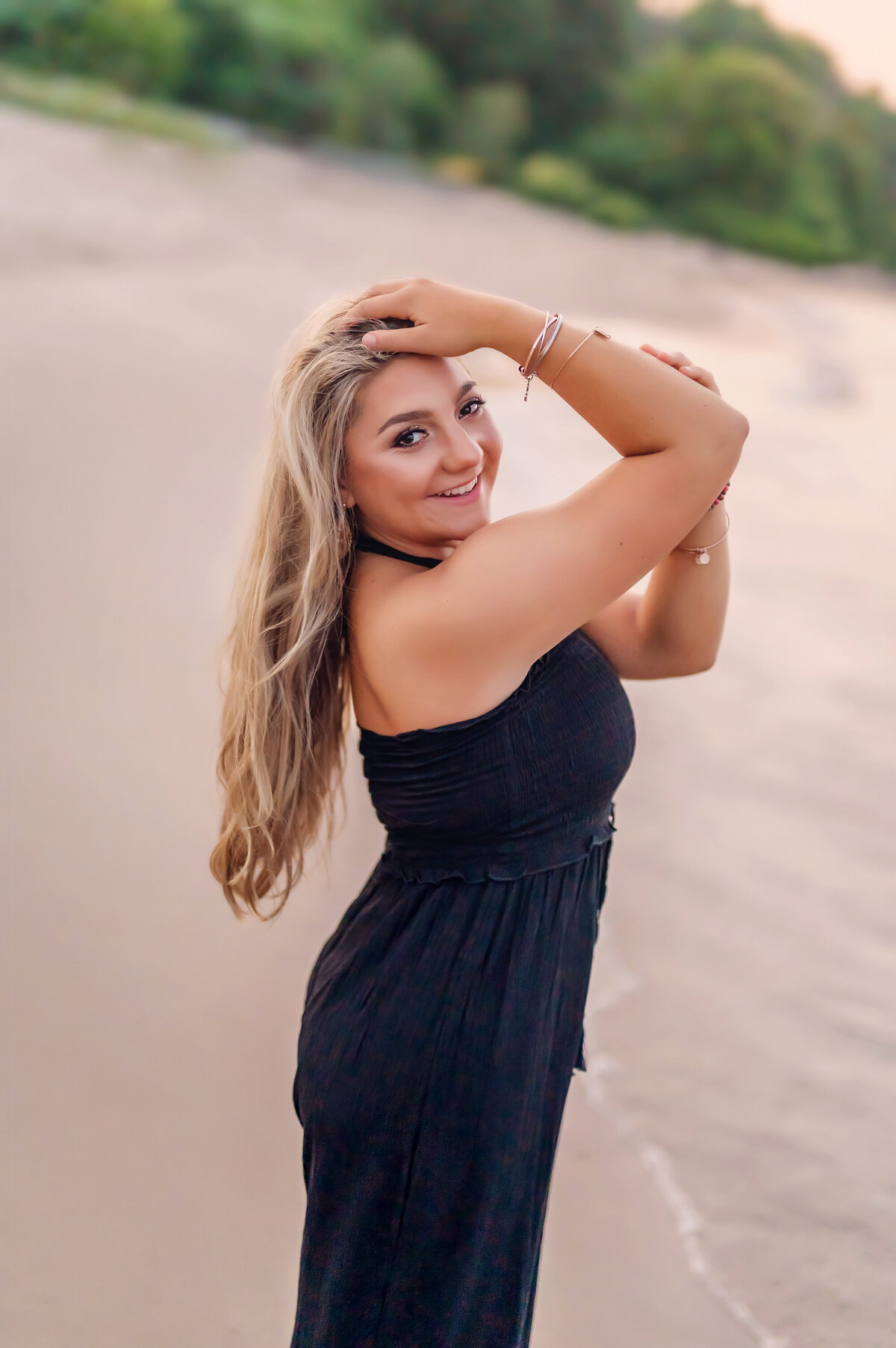 A young lady from Brookfield Central High School poses for her senior portraits wearing a black jumpsuit on the shore of Lake Michigan.