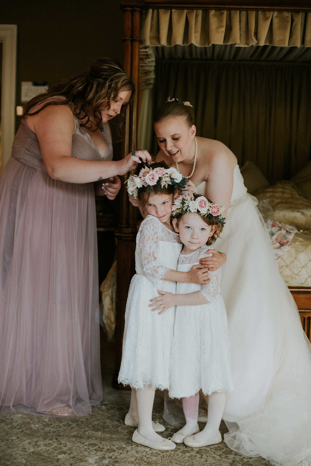 Flower girls hug while bride secures flower crown at Laurel Hall Wedding