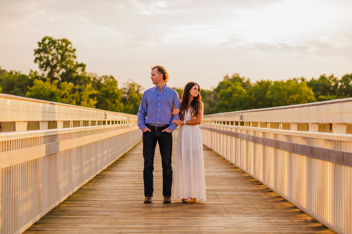 photo of man and woman on a bridge at sunset