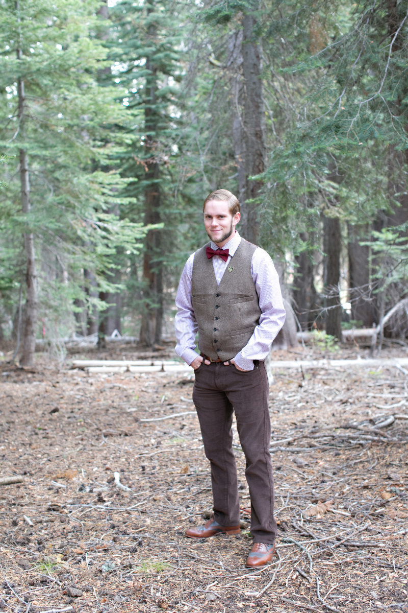 Groom wearing bowtie and vest standing in Tahoe forest