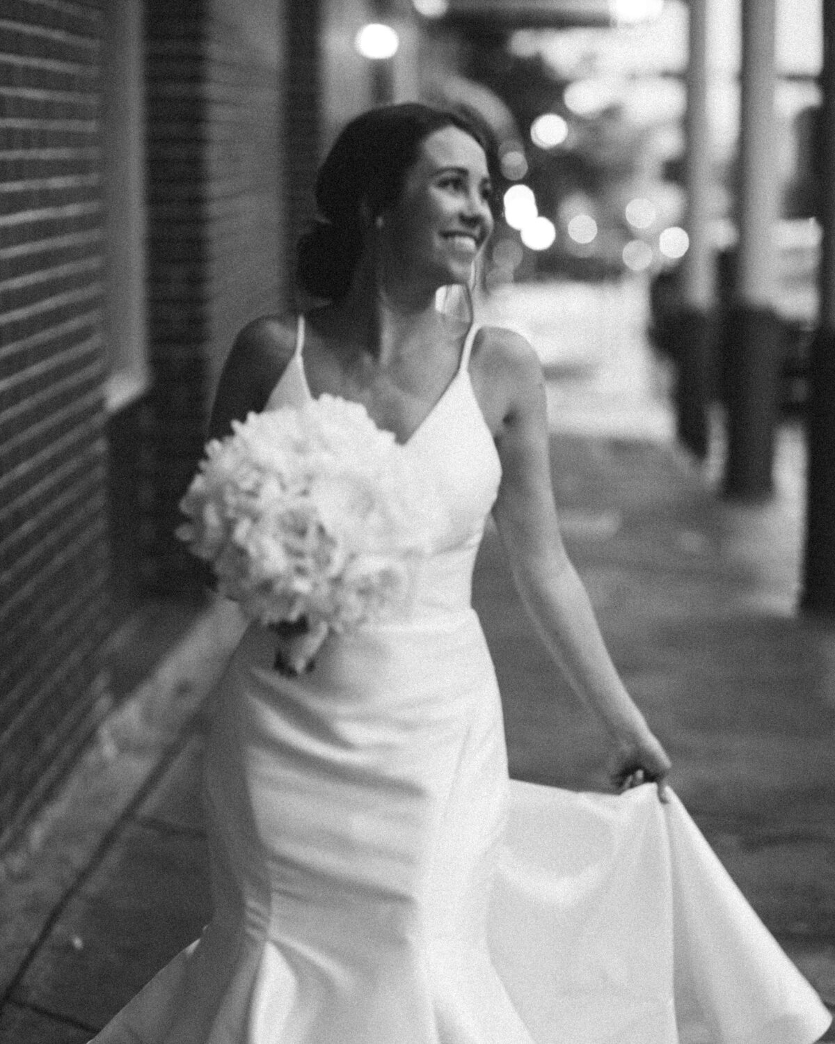 Bride smiles as she walks down a sidewalk on her wedding day