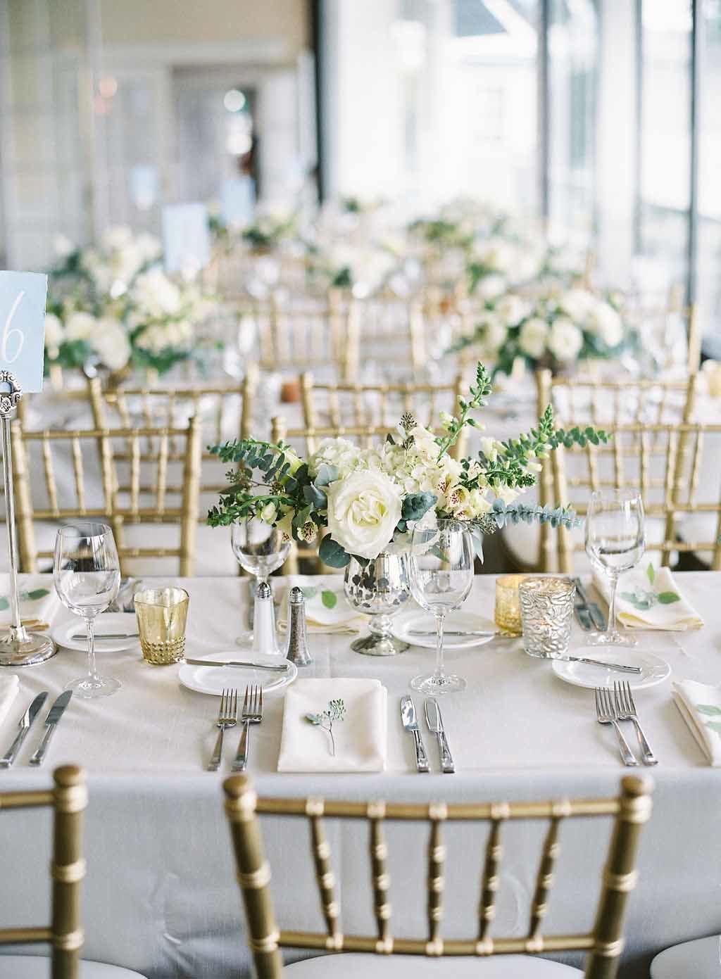 wedding reception tabes with white linens, gold chivari chairs, and white floral centerpieces