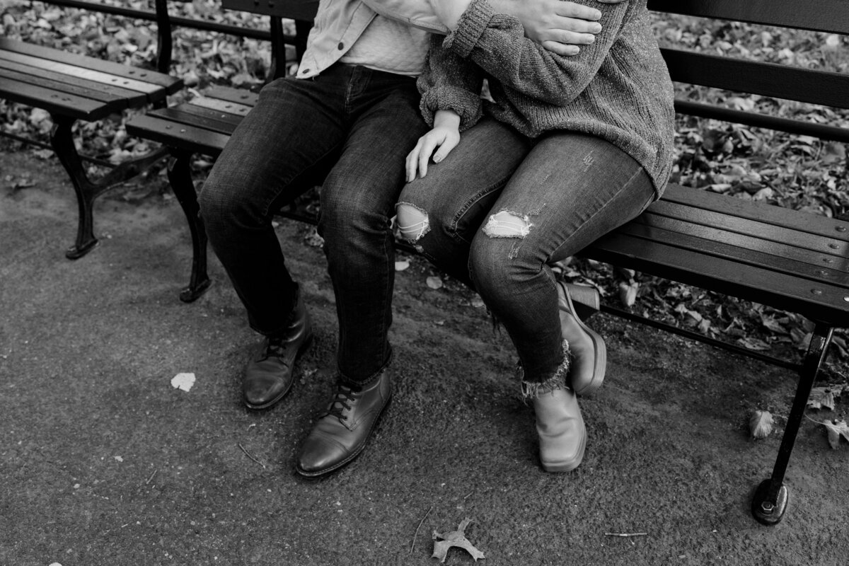 black and white image of two people sitting on a park bench