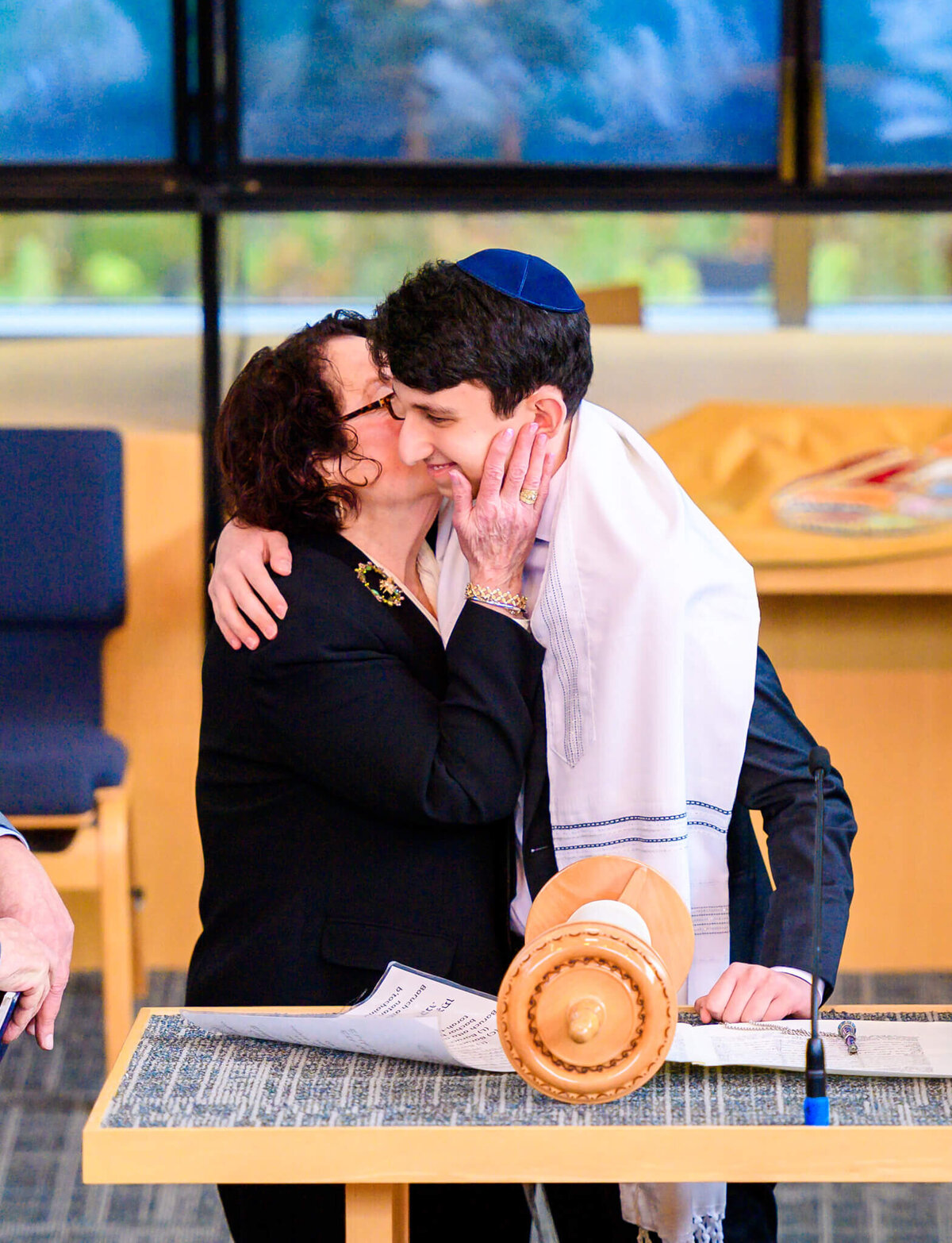 A woman kisses the cheek of a boy during his bar mitzvah at the bimah