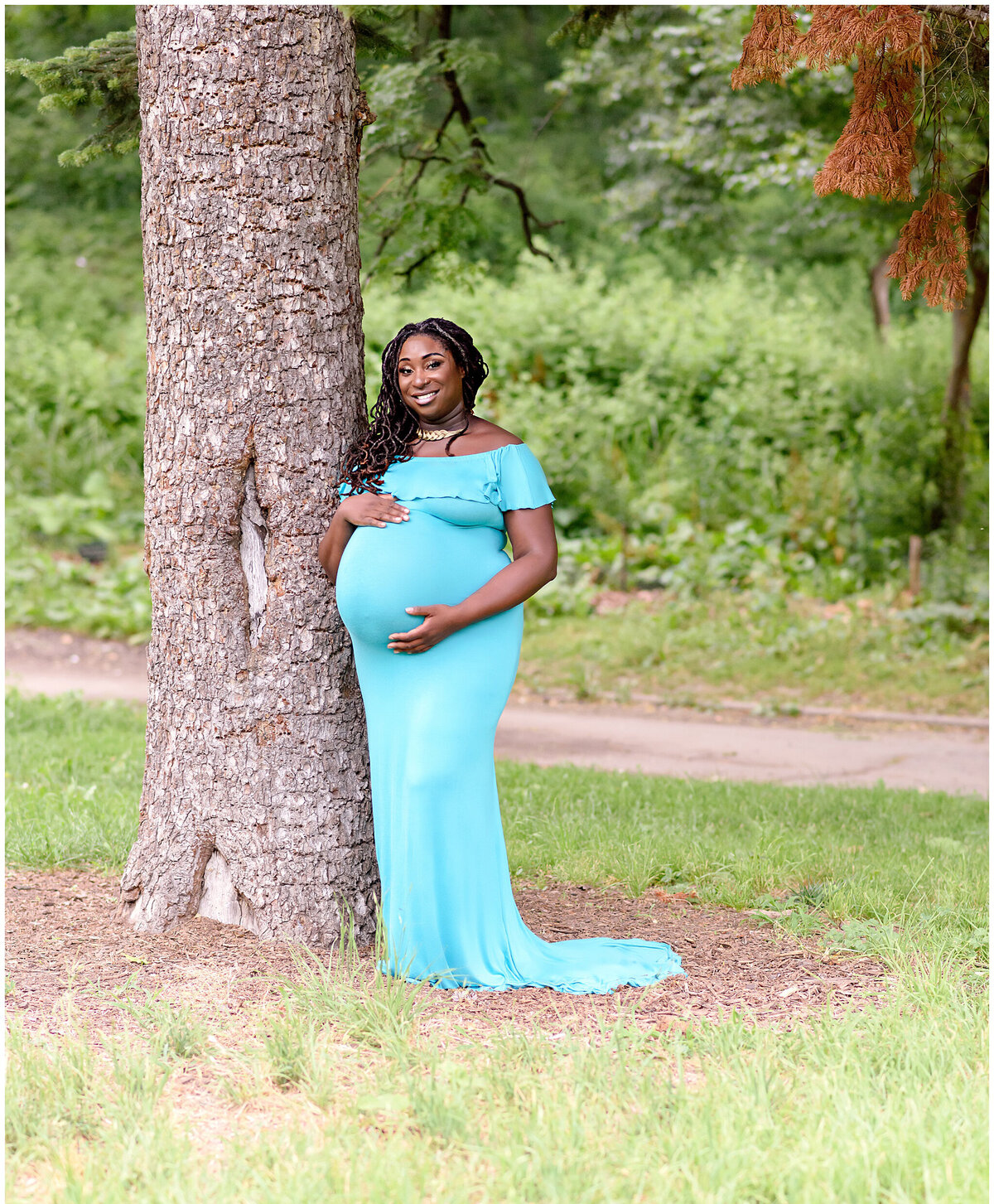woman standing next to tree at lincoln terrace park in brooklyn holding tummy looking at camera