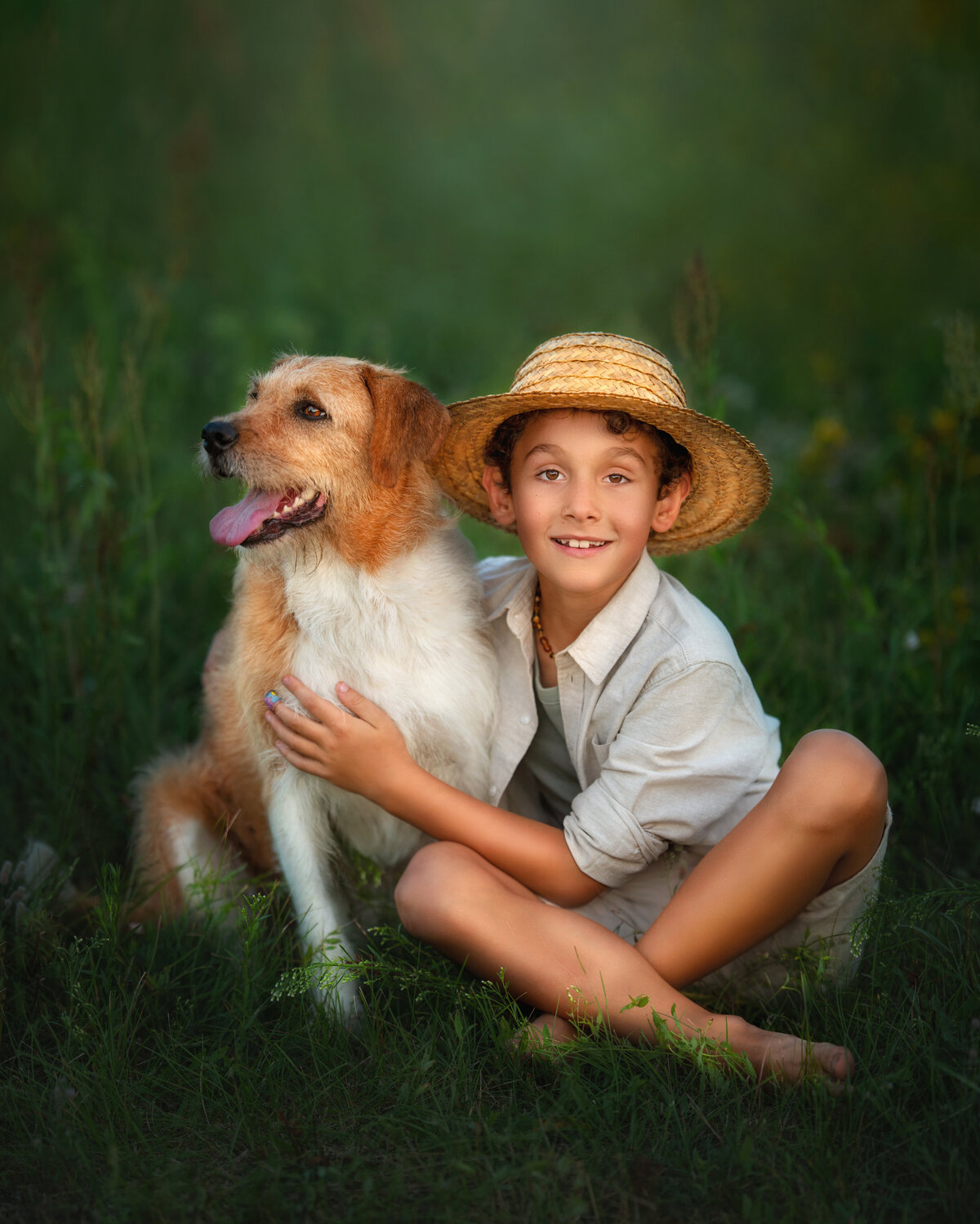 Kid in linen outfit and straw hat holding  scruffy farm dog