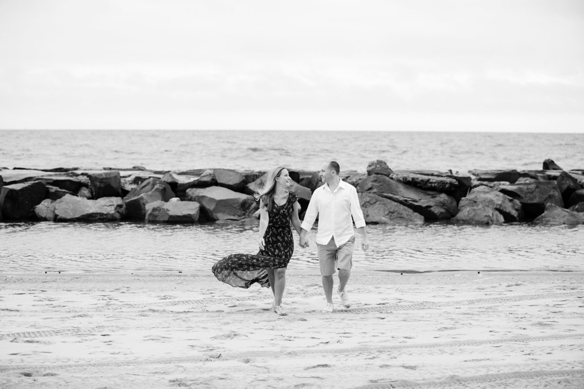 engaged couple walk on beach at asbury park